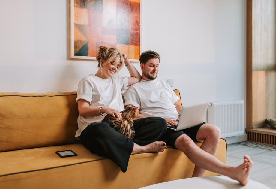 male and female couple sitting on a couch looking at a laptop