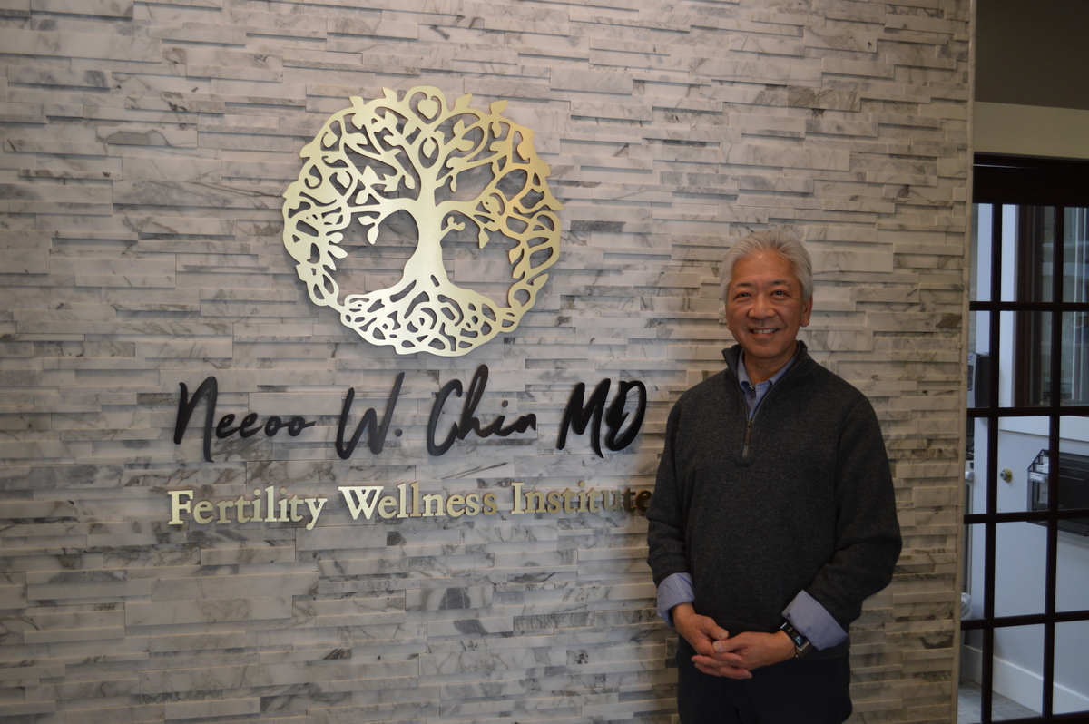 Dr. NeeOo Chin in front of sign