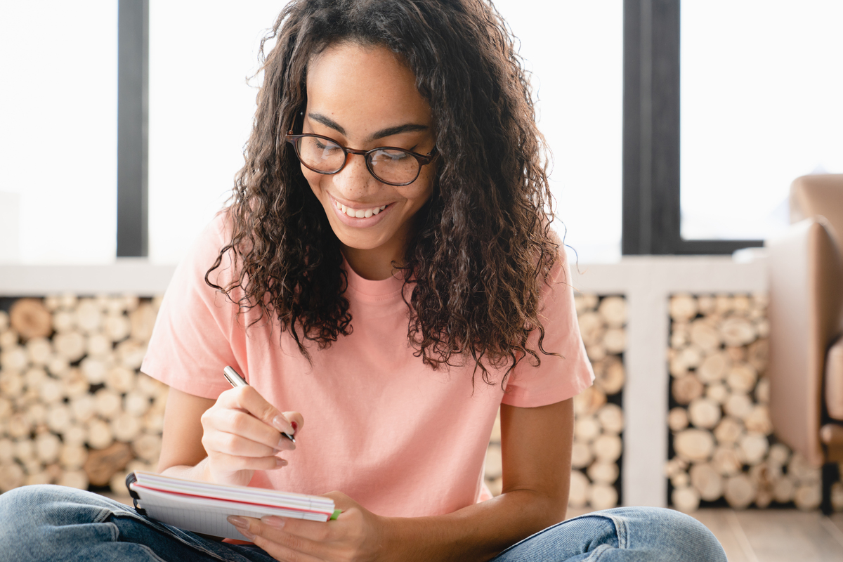 woman writing in notebook, smiling