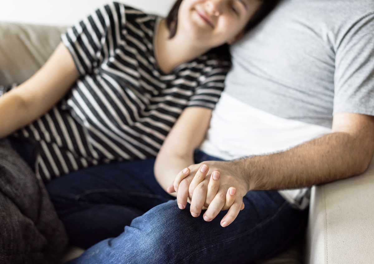 a couple holding hands on the couch