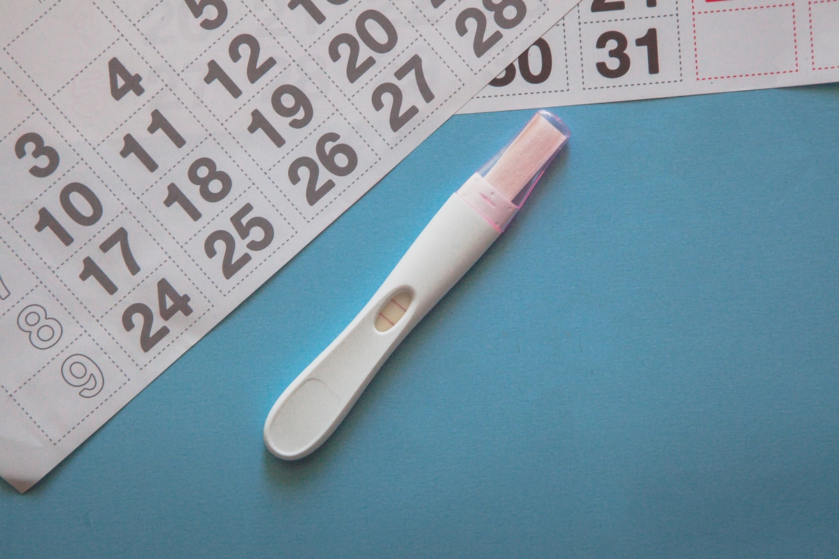 positive pregnancy test next to a calendar