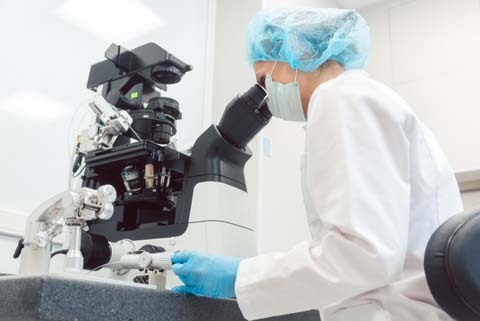 technician looking through microscope 